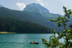 An illustrative photo of a boat floating on a lake with mountains in the background