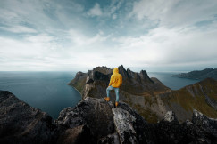 An illustrative photo of a man standing on a mountain peak.