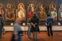 An illustrative photo of a group of people standing in front of a painting
