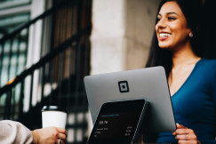 An illustrative photo of a woman with a computer smiling to another person