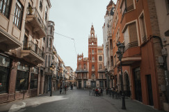An illustrative photo of a city street lined with tall buildings and a clock tower