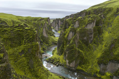 An illustrative photo of a green mossy cliff with river in the middle