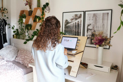 An illustrative photo of a woman standing in front of a table with a laptop.