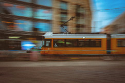 An illustrative photo of a yellow tram traveling down a street.