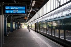 An illustrative photo of a man walking near a train on a train station 