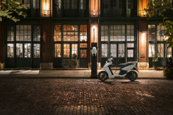 An illustrative photo of motor scooter parked beside a brown building.