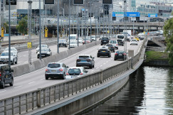 An illustrative photo of a highway filled with lots of traffic next to a river