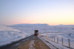 An illustrative photo of a semi truck driving down a snowy road.