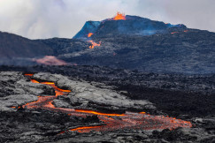 An illustrative photo of a volcano with lava floating down the side of it