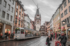 An illustrative photo of people walking on sidewalk near a tram.