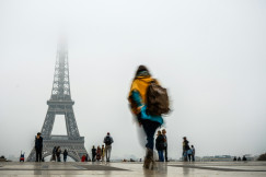 An illustrative photo of people walking near Eiffel Tower during a foggy day