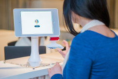 An illustrative photo of a woman at the registration desk near a monitor 