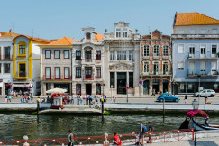 An illustrative photo of people walking near buildings beside water