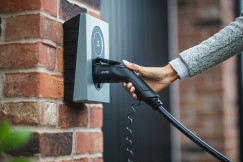 An illustrative photo of a person charging an electric car with a charger