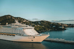 An illustrative photo of a white cruise ship on sea near a coast.
