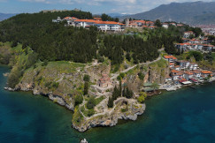 An illustrative photo of houses on a mountain near a body of water.
