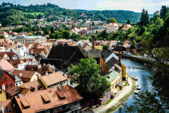 An illustrative photo of a river running through a small town next to a lush green hillside.
