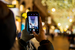 An illustrative photo of a person taking a picture of Christmas lights
