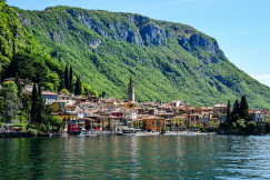 An illustrative photo of a town by a body of water with mountain in the background