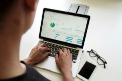 An illustrative photo of a person using laptop with graphs on it