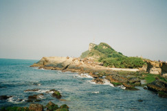 An illustrative photo of a rocky shore with a small island.