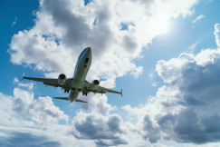 An illustrative photo of an airplane flying in the sky with clouds