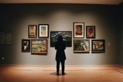 An illustrative photo of a woman standing in front of paintings