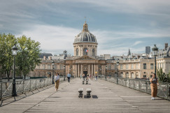 An illustrative photo of people walking on sidewalk near buildings.