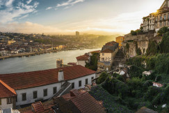 An illustrative photo of white and brown houses on a hill near a river.