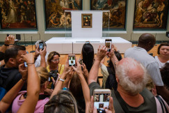 An illustrative photo of people taking photos of the Mona Lisa painting.