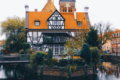 An illustrative photo of a white and orange house in the middle of a body of water.
