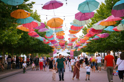 An illustrative photo of people walking down a street under umbrellas.
