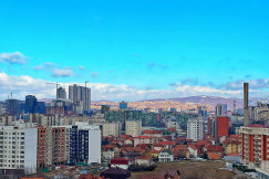 An illustrative photo of a city with tall buildings with mountains in the background.