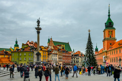 An illustrative photo of people walking on a square with a Christmas tree.