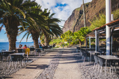 An illustrative photo of people sitting on chairs near beach.