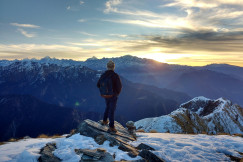 An illustrative photo of person standing on top of the mountain facing sunrise.