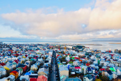 An illustrative photo of houses of different colours near the sea.