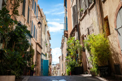 An illustrative photo of cars parked on sidewalk in between buildings.