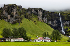 An illustrative photo of white houses near a green rocky mountain.