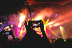 An illustrative photo of a person holding smartphone taking video of a concert.