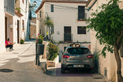 An illustrative photo of a car parked near a building.
