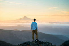 An illustrative photo of a man standing on top of a mountain.