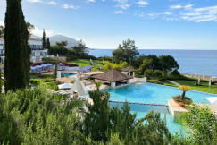 An illustrative photo of a white and brown house near a swimming pool.