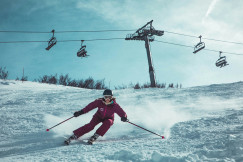 An illustrative photo of a person skiing under cable cars.