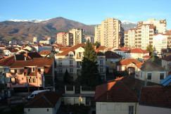 An illustrative photo of city buildings with mountains in the background.