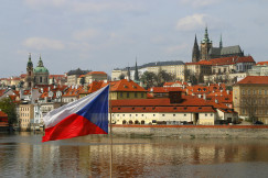 An illustrative photo of red and white concrete buildings near a body of water.