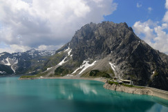 An illustrative photo of a lake near mountain under white clouds.