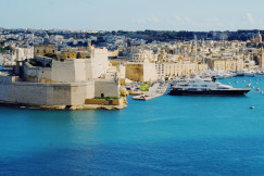 An illustrative photo of a white and black yacht at dock near a city.