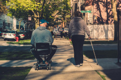 An illustrative photo of a man on a stroller and a woman with a stick.