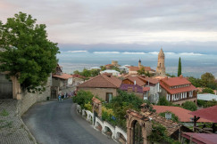 An illustrative photo of a road with buildings and trees by a body of water.